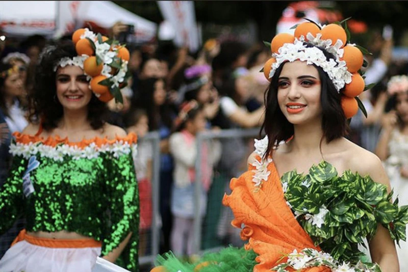 صویری از 2 دختر جوان که برای جشنواره شکوفه پرتقال آلانیا، لباس های نمادی با تزیین پرتقال پوشیده‌اند