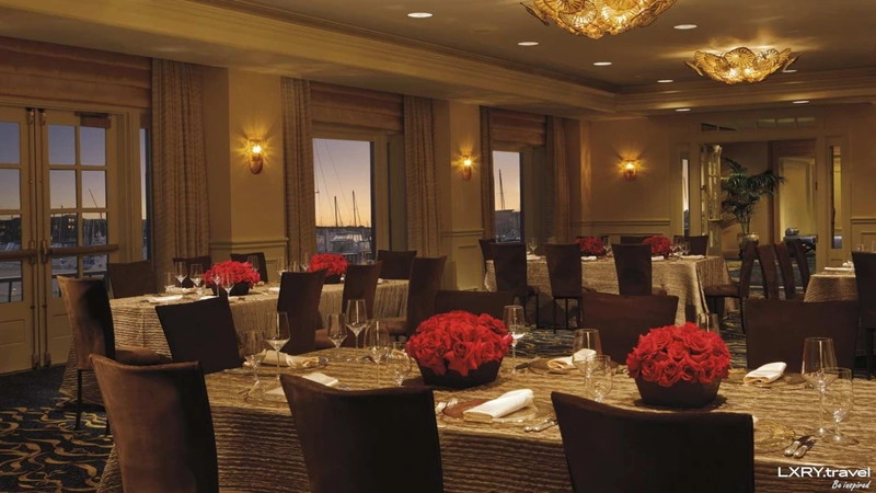 فضای داخلی رستوران هتل ۵ ستاره ریتز کارلتون استانبول، با میزهای چیده‌شده برای شام، گل‌های رز قرمز و نورپردازی گرم داخلی. 