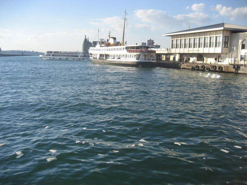  نمایی از اسکله کادیکوی استانبول با یک کشتی شهری (Vapur) پهلو گرفته و ایستگاه تاریخی حیدرپاشا در پس‌زمینه، نقطه شروع گشت‌وگذار در کادیکوی.